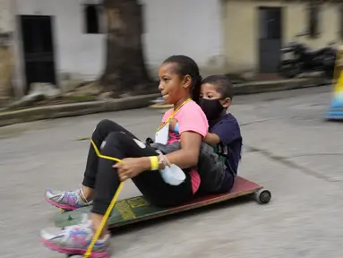 Anak-anak berpartisipasi dalam perlombaan jalanan tradisional "carruchas", sebutan untuk mobil kayu darurat di Caracas, Venezuela, Sabtu (18/12/2021). Anak-anak menikmati perlombaan yang menandai 10 tahun melestarikan tradisi ini. (AP Photo/Ariana Cubillos)