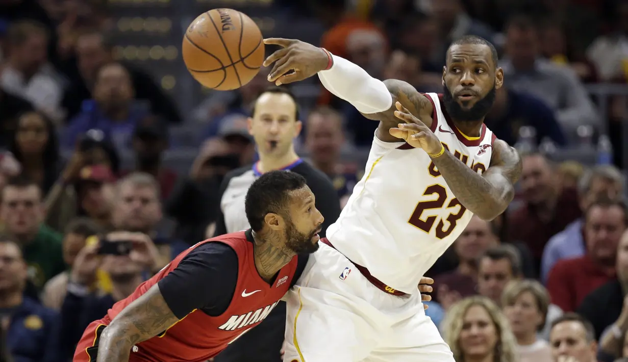 Pemain Cleveland Cavaliers, LeBron James (23) memberikan umpan melewati adangan pemain Miami Heat, James Johnson (16) pada lanjutan NBA basketball game, di Quicken Loans Arena, Cleveland, (28/11/2017). Cavs menang 108-97. (AP/Tony Dejak)