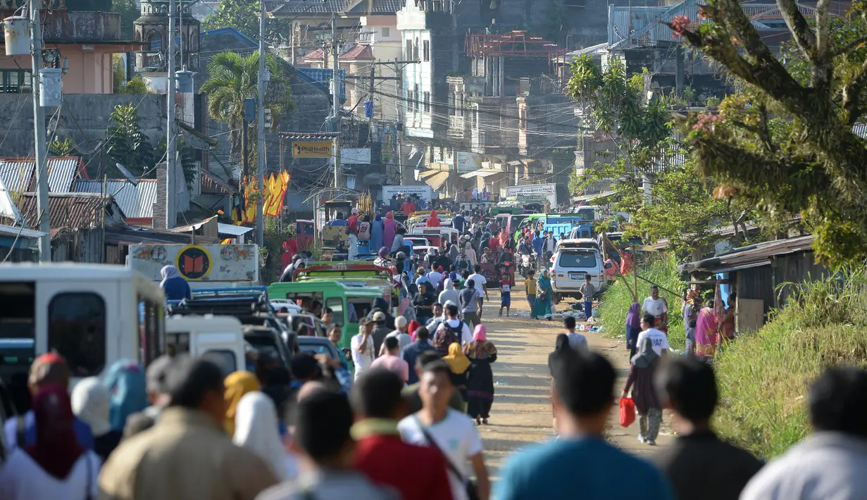 Ribuan orang berjalan memasuki Kota Marawi, Mindanao, Filipina, Minggu (1/4). Pihak berwenang mengizinkan warga mengunjungi rumah mereka yang hancur di area pertempuran militer Filipina dengan militan ISIS. (TED ALJIBE/AFP)