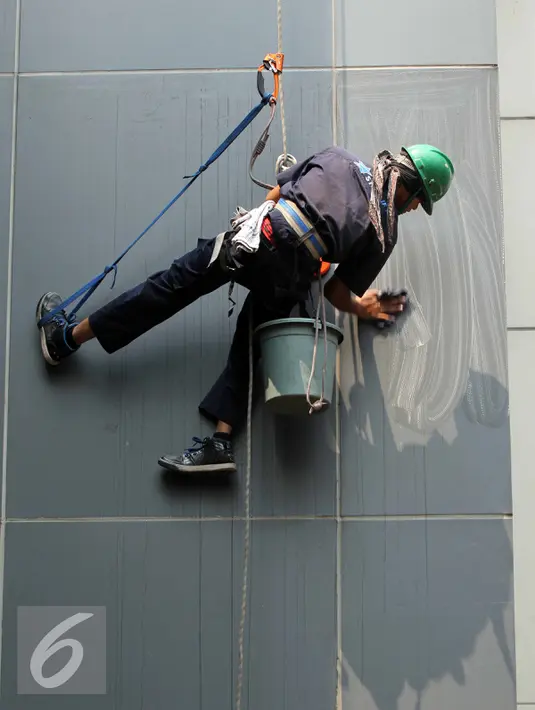 Pekerja membersihkan kaca gedung bertingkat di Jakarta, Senin (25/8/2015). Untuk meminimkan kecelakaan, Kementerian Tenaga Kerja dan Transmigrasi telah mencanangkan bulan Keselamatan dan Kesehatan Kerja (K3) pada tahun 2014. (Liputan6.com/Helmi Afandi)