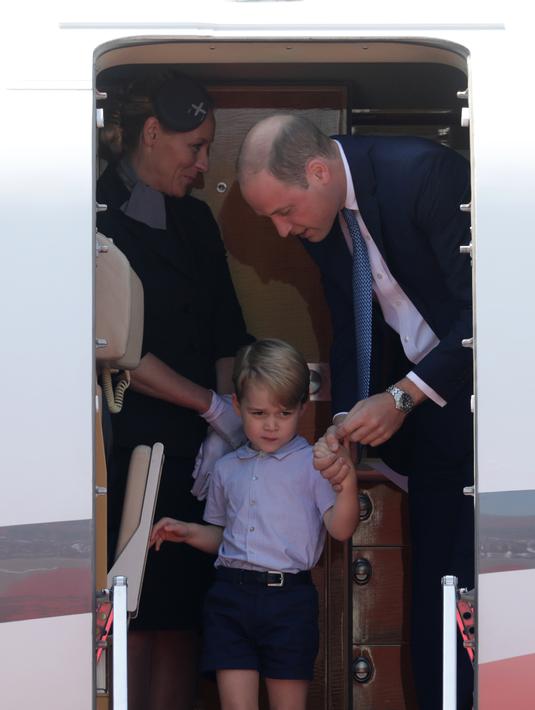 Pangeran William membujuk putranya, Pangeran George untuk turun dari pesawat sesampainya di bandara Tegel, Berlin, Rabu (19/7). Ikut dalam tur keluarga kerajaan Inggris, George kelihatan lelah dan mengantuk saat turun pesawat. (Kay Nietfeld/POOL/AFP)