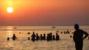 Pengunjung berenang sambil menikmati pemandangan matahari terbenam di Pantai Santa Maria Del Focalo, Pulau Sisilia, Italia, 7 Agustus 2017. Pantai Santa Maria Del Focalo menjadi salah satu tujuan objek wisata favorit di Italia. (ludovic MARIN/AFP)