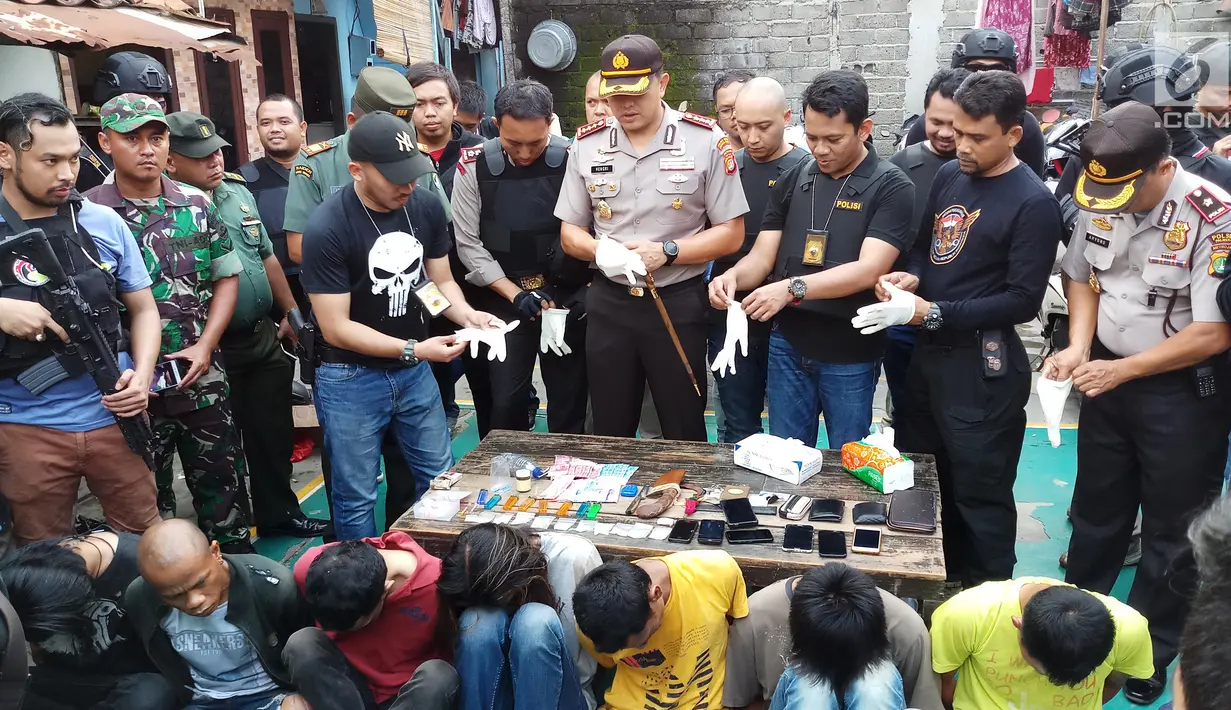 Petugas menunjukkan barang bukti dalam penggerebekan Kampung Boncos, Kota Bambu Selatan, Palmerah Jakarta Barat, Rabu (7/2). (Liputan6.com/ Ady Anugrahadi)