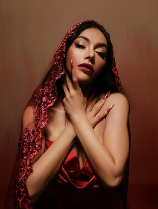 Wajahnya dipulas dengan makeup bold glam berlipstik merah gelap yang berani [@denadaindonesia]