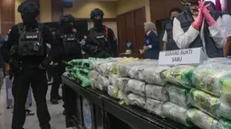 Petugas Badan Narkotika Nasional (BNN) menjaga barang bukti narkotika saat pengungkapan hasil Operasi Saber Bersinar 2026 di Kantor BNN RI, Jakarta, Selasa (19/05/2026). (merdeka.com/Arie Basuki)