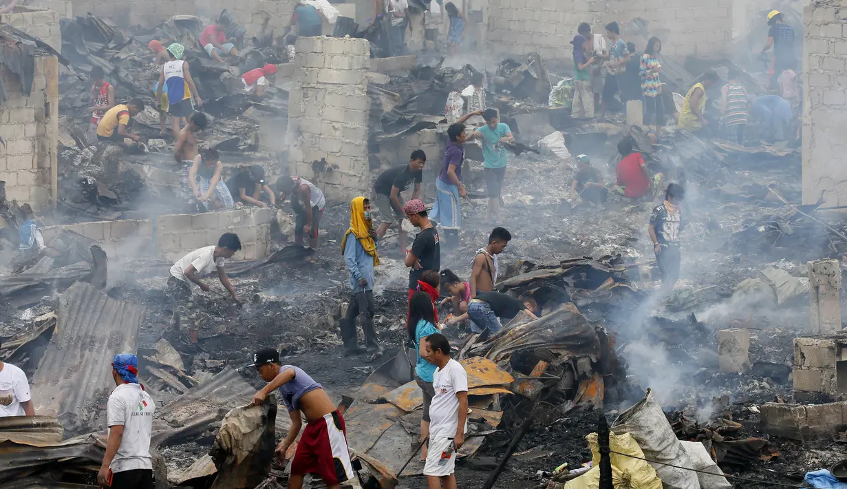 Warga mencari barang yang tersisa usai terjadi kebakaran yang melanda permukiman mereka di wilayah Navotas, Metro Manila, Filipina, Selasa (10/1). (AP Photo/ Bullit Marquez)