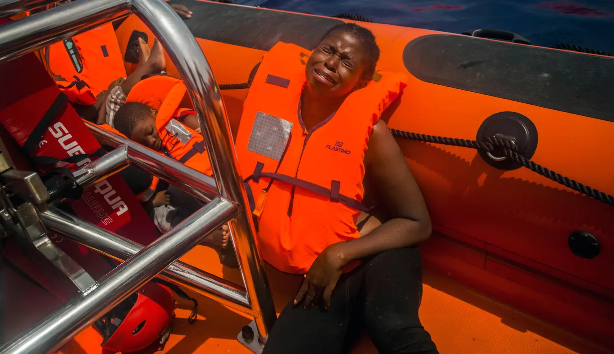 Seorang imigran Afrika sub-Sahara menangis usai diselamatkan dari atas perahu karet di tengah Laut Mediterania, lepas pantai Libya, Selasa (25/7). Di perahu karet itu, petugas penyelamat dari LSM Spanyol mememukan 13 mayat. (AP/Santi Palacios)