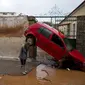 Sebuah mobil ringsek akibat terdorong arus banjir di Mandra, Yunani, pada 15 November 2017. (AP Photo/Petros Giannakouris)