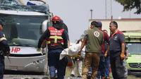 Petugas penyelamat mengevakuasi jenazah di lokasi kecelakaan maut, di mana sebuah kereta barang menabrak bus tingkat dua di Atlacomulco, Meksiko, Senin (8/9/2025). (Dok. AP/Ramses Mercado Valdes)