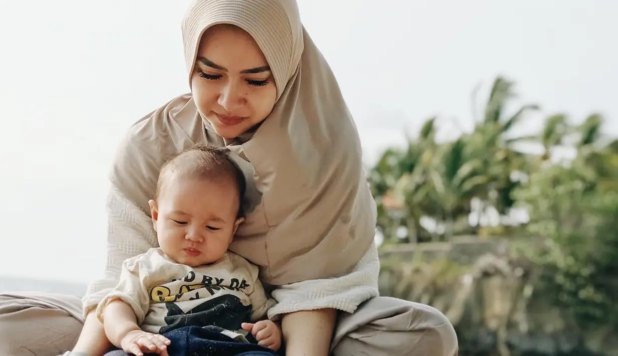 Saat bermain di pantai bersama sang buah hati saja Aryani tampil dengan penuh kesederhanaan. Ia memakai hijab langsung pakai yang dipadukan dengan baju santainya. (Instagram/aryanifitriana24)