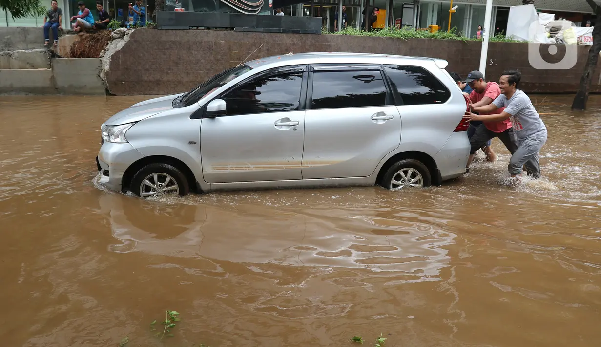Sejumlah orang memindahkan mobil yang terendam banjir di kawasan Kemang, Jakarta, Kamis (2/1/2020). Banjir yang melanda Jakarta dan sekitarnya mengakibatkan banyak kendaraan terendam air. (Liputan6.com/Herman Zakharia)