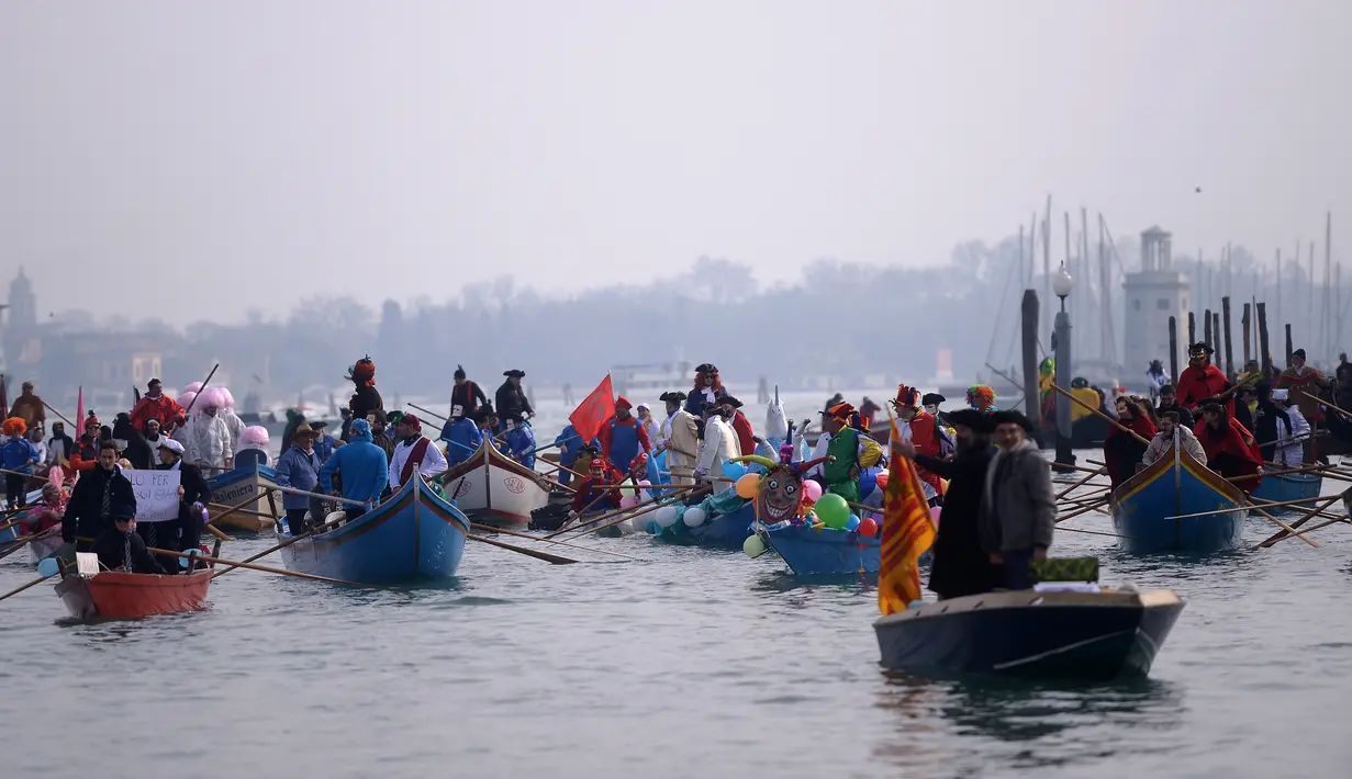 Peserta mengenakan kostum sambil mendayung perahu menyusuri Grand Canal pada parade upacara pembukaan karnaval Venesia di Italia, 28 Januari 2018. Karnaval Venesia pertama kali diselenggarakan pada abad ke-11.  (AFP Photo / FILIPPO MONTEFORTE)
