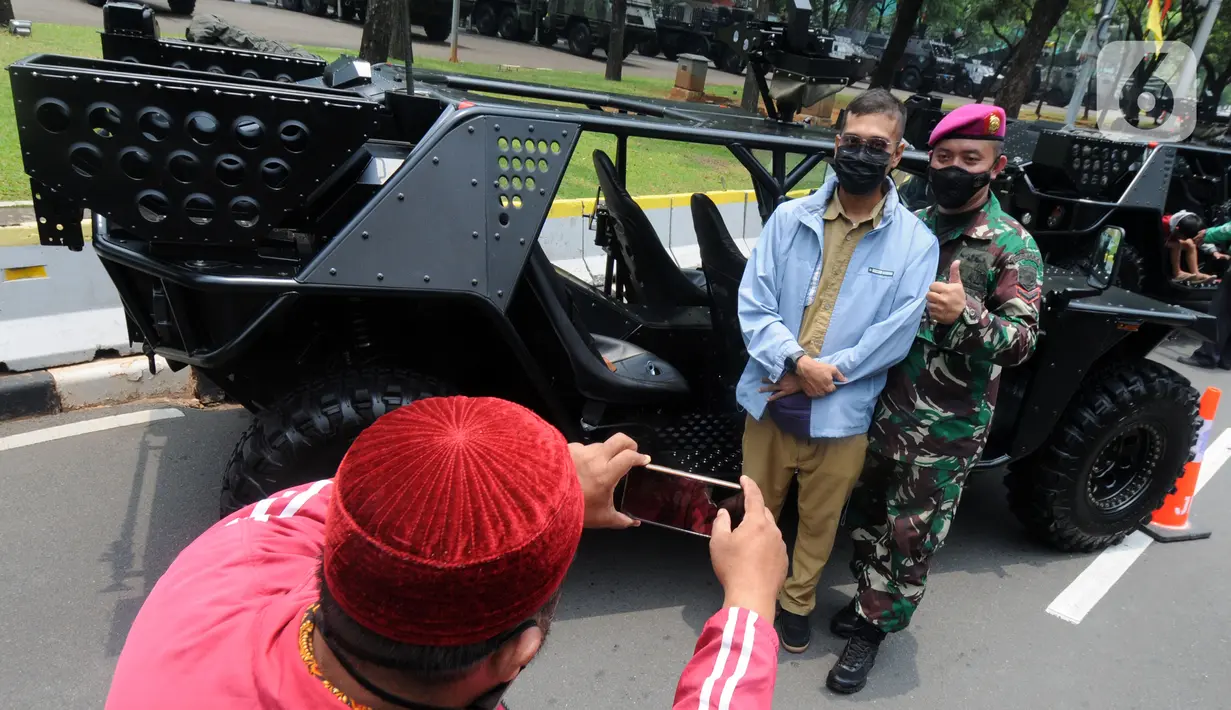 Warga berfoto dengan kendaraan taktis TNI yang dipamerkan di depan Istana Merdeka, Jakarta, Senin (4/10/2021). Ratusan alat utama sistem persenjataan (Alutsista) TNI dipamerkan sepanjang pinggir jalan sekeliling kawasan Monas dalam rangka peringatan HUT ke-76 TNI. ​(merdeka.com/Arie Basuki)