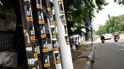 Stiker bergambar #1 masih menempel di beberapa tiang di sekitar Jalan Otista Raya, Jakarta, Senin (13/1). Hingga H-2 Pilkada DKI Jakarta, alat peraga kampanye masih terlihat di beberapa ruas jalan Ibukota. (Liputan6.com/Helmi Fithriansyah)