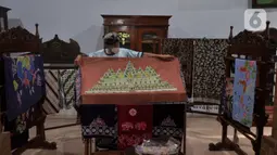 Adiwinarto menunjukkan karya batik di galeri Lumbini di Dusun Tingal, Desa Wanurejo, Kecamatan Borobudur, Kabupaten Magelang, Jawa Tengah, Selasa (17/5/2022). Batik tulis Lumbini menawarkan motif yang terinspirasi dari relief Candi Borobudur, pinisi, liman kembar, mandala, dan daun bodi. (merdeka.com/Iqbal S. Nugroho)