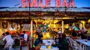 Orang-orang duduk di sebuah bar , saat para turis memanfaatkan program "Kotak Pasir Phuket" untuk pengunjung yang divaksinasi penuh terhadap virus corona Covid-19 di pulau Phuket Thailand (25/10/2021). (AFP/Mladen Antonov)
