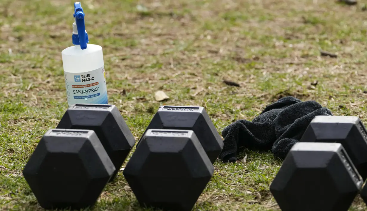 Botol desinfektan diletakkan di dekat peralatan gym di sebuah taman di pinggiran timur Sydney, pada 14 September 2021. Pelatih kebugaran telah mengubah taman kawasan tepi laut di Rushcutters Bay menjadi gym luar ruangan untuk menyiasati pembatasan lockdown karena pandemi covid-19. (AP/Mark Baker)