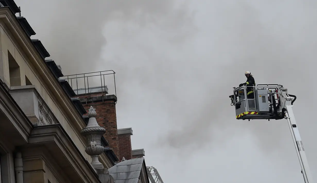 Petugas pemadam berusaha mencapai lantai atas Hotel Ritz yang terbakar, Paris, Selasa (19/1). Api mulai terlihat di lantai tujuh hotel yang telah ditutup sejak Agustus 2012 untuk dilakukan renovasi besar-besaran. (AFP PHOTO/Lionel Bonaventure)