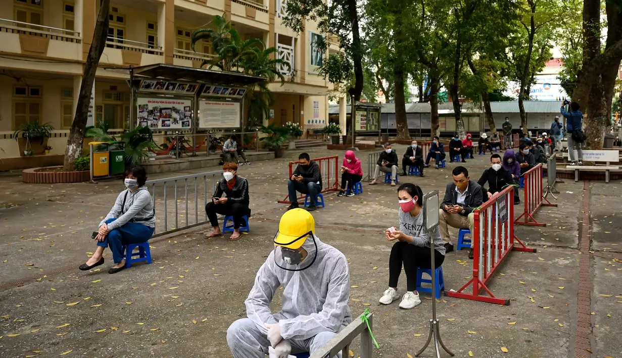 Penduduk memakai masker mengantre dengan tertib saat akan mengikuti pengujian Covid-19 di pusat pengujian dekat rumah sakit Bach Ma, Hanoi, Vietnam (31/3/2020). Warga Vietnam antusias mengikuti tes Covid-19 dengan tertib di tengah masifnya penyebaran Covid-19 di dunia. (AFP/Manan Vatsyayana)