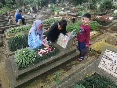 Warga berziarah di makam keluarganya di Tempat Pemakaman Umum (TPU) Dreded, Bogor, Jawa Barat, Minggu (15/2/2026). Jelang bulan suci Ramadan, sejumlah Tempat Pemakaman Umum (TPU) mengalami lonjakan peziarah. (merdeka.com/Arie Basuki)