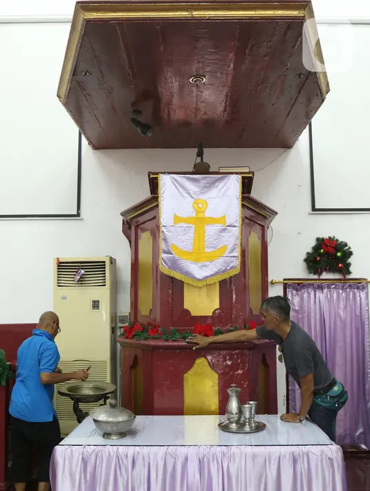 Pekerja menghias altar Gereja Tugu dengan ornamen Natal, Jakarta, Senin (23/12/2019). Sejumlah perlengkapan ibadah telah disiapkan untuk menyambut Natal. (Liputan6.com/Herman Zakharia)