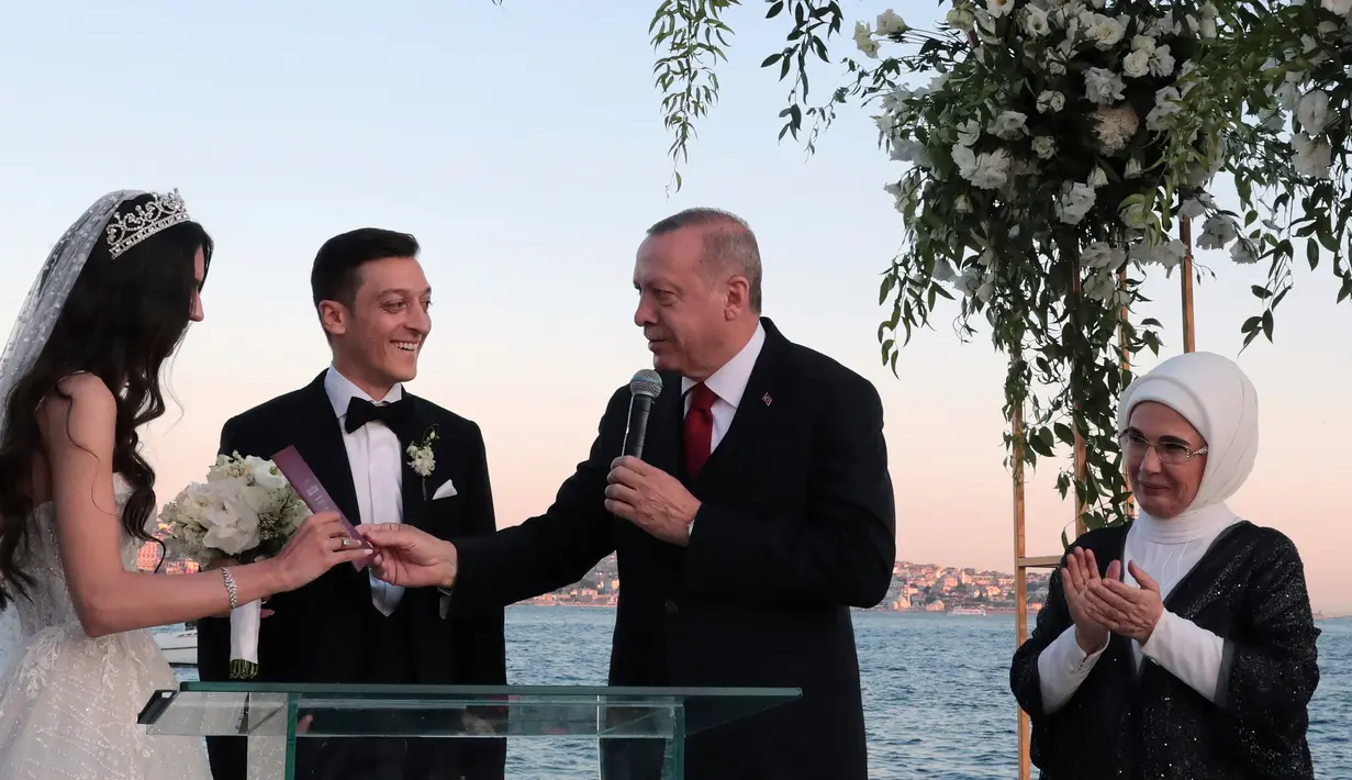 Presiden Turki Recep Tayyip Erdogan (kedua kanan) menyerahkan buku nikah kepada gelandang Arsenal asal Jerman, Mesut Ozil dan Amine Gulse saat menghadiri seremoni pengucapan janji pernikahan mereka di sebuah hotel mewah di Istanbul, Jumat (7/6/2019). (Presidential Press Service via AP, Pool)
