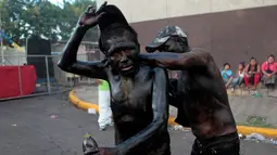 Dua orang pria saling melumuri oli di tubuhnya saat mengambil bagian dari perayaan menghormati santo pelindung Managua, Santo Domingo de Guzman Managua , Nikaragua, (9/8). Perayaan ini berlangsung dari 31 Juli dan 9 Agustus.  (REUTERS / Oswaldo Rivas)