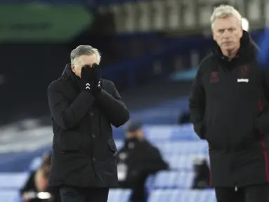 Pelatih Everton, Carlo Ancelotti (kiri) menutup wajahnya saat menyaksikan pemainnya bertanding melawan West Ham pada pertandingan lanjutan Liga Inggris di Goodison Park, Sabtu (2/1/2021). Everton tumbag atas West Ham 0-1. (Jan Kruger, Pool via AP)