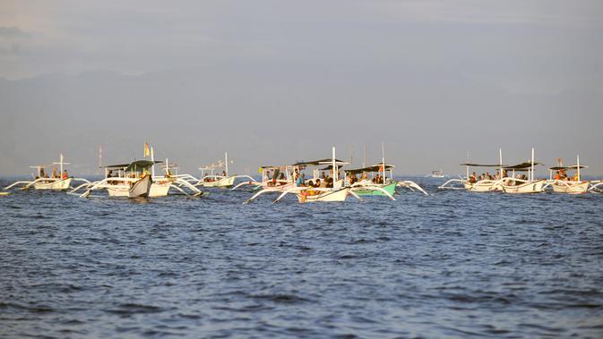 Wisatawan di atas perahu selama tamasya menyaksikan lumba-lumba di perairan Pantai Lovina di Singaraja, Bali, Jumat (30/10/2020). Pantai Lovina merupakan salah satu destinasi pariwisata di Bali yang sering dikunjungi untuk menikmati matahari terbit dan lumba-lumba di laut lepas (SONNY TUMBELAKA/AFP)