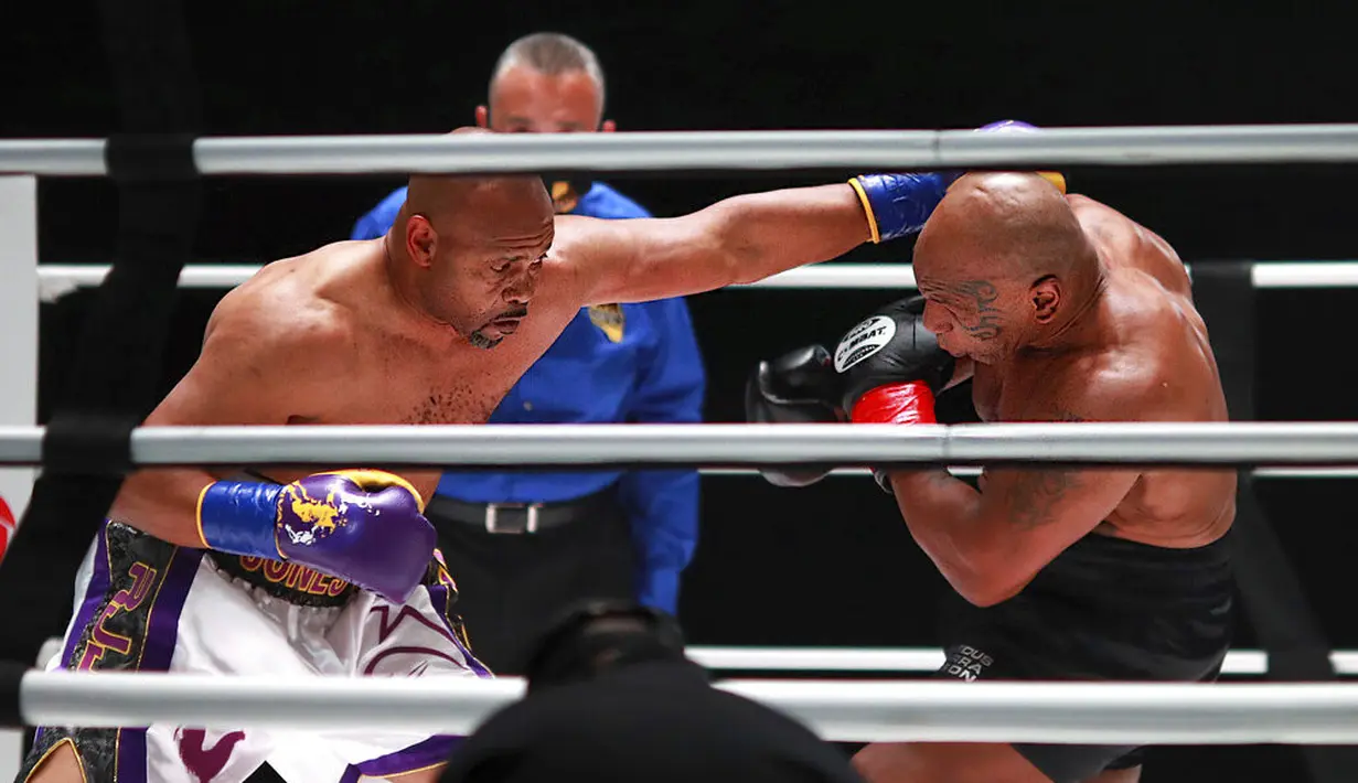 Roy Jones Jr melakukan pukulan terhadap Mike Tyson pada pertarungan tinju eksibisi di Los Angeles, Amerika Serikat, Sabtu (28/11/2020). Pertandingan berakhir tanpa pemenang alias imbang. (Joe Scarnici/Triller via AP)