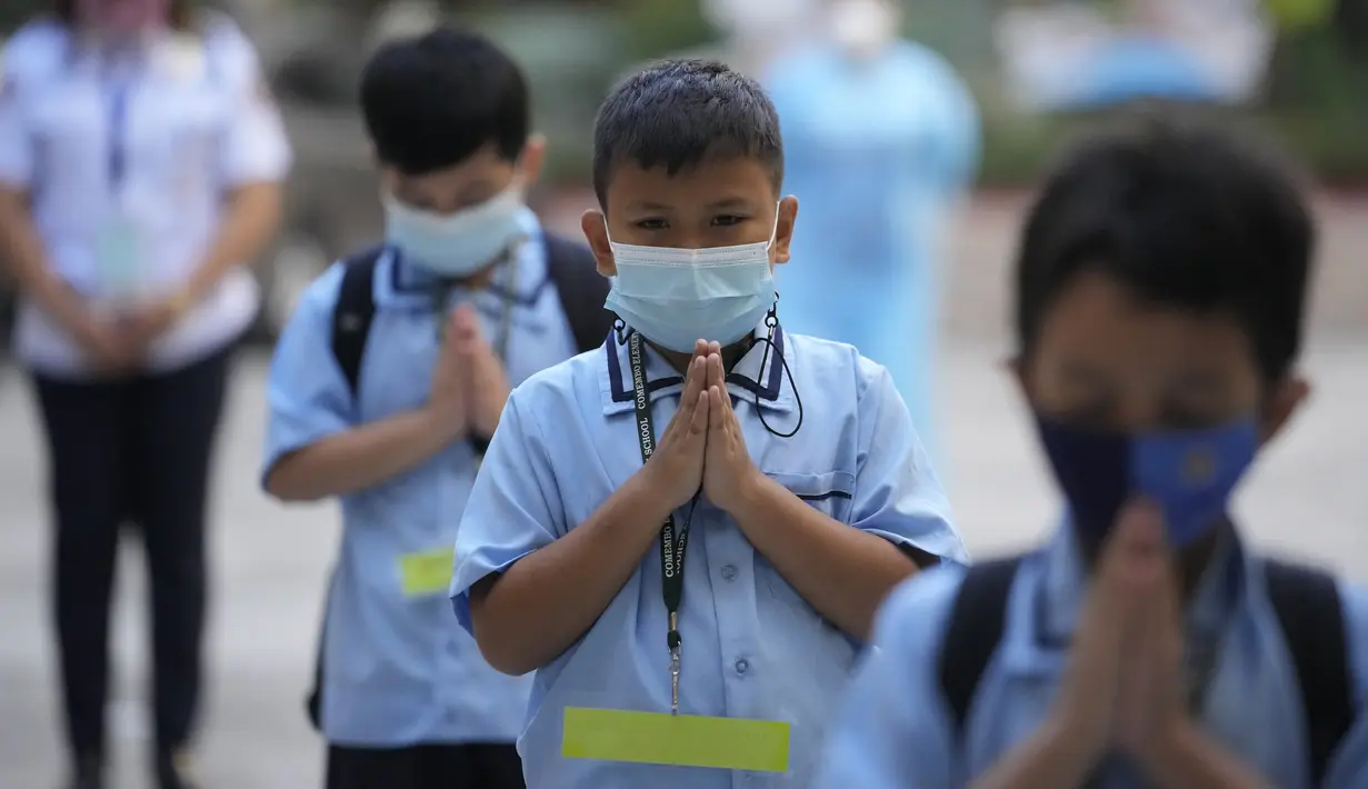 Siswa yang memakai masker berdoa pada hari pertama kelas tatap muka di sekolah dasar Comembo di kota Makati, Filipina, Senin (6/12/2021). Beberapa sekolah di Manila diizinkan dibuka kembali setelah berbulan-bulan lamanya karena kasus COVID-19 terus menurun di negara tersebut. (AP Photo/Aaron Favila)