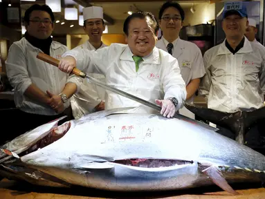 Pemilik restoran, Kiyoshi Kimura tersenyum sebelum memotong tuna sirip biru dengan berat 200 kg di depan restorannya, Tsukiji, Jepang, Selasa (5/1). Kimura mendapatkan tuna sirip biru dengan harga 14 juta yen atau Rp 1,6 miliar. (REUTERS/Toru Hanai)