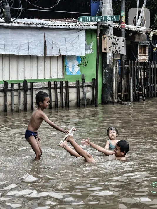 Anak-anak bermain air saat banjir menggenangi Jalan Jatinegara Barat, Jakarta, Senin (8/2/2021). Banjir yang menggenangi Jalan Jatinegara Barat terjadi akibat luapan Kali Ciliwung yang dipicu hujan deras di Jakarta dan Bogor sejak dini hari tadi. (merdeka.com/Iqbal S. Nugroho)
