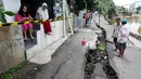 Sejumlah warga mengamati jalan retak di Kelurahan Kebon Manggis, Kecamatan Matraman, Jakarta Timur, Jumat (16/2). Tak hanya retak, jalan yang tepat berada di pinggir anak sungai Ciliwung itu juga sempat mengalami longsor. (Liputan6.com/Johan Tallo)