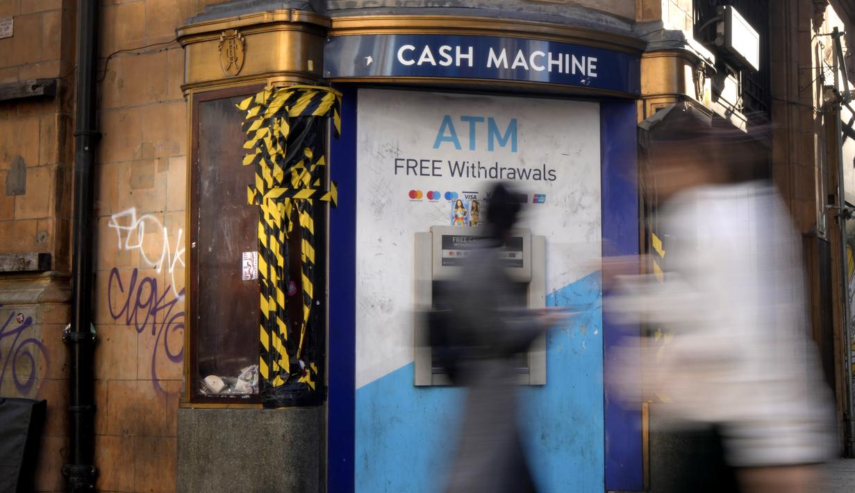 Pejalan kaki melewati mesin ATM di Oxford Street di London, Rabu (15/2/2023). Tingkat inflasi Inggris turun untuk bulan ketiga berturut-turut pada Januari, meningkatkan optimisme bahwa krisis biaya hidup telah memuncak dan harga akan turun tajam akhir tahun ini. (AP Photo/Kirsty Wigglesworth)