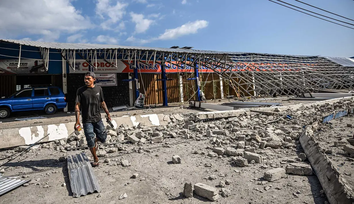 Seorang pria berjalan di tengah puing-puing bangunan yang rusak akibat gempa berkekuatan magnitudo 7,7 di Borong, Manggarai Timur, Nusa Tenggara Timur, Minggu, 16 Agustus 2026.. (AFP/ Juni Kriswanto)