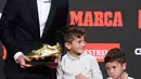 Pemain Barcelona, Lionel Messi bersama kedua putranya berpose setelah menerima trofi Sepatu Emas keenamnya selama acara penyerahan di Antiga Fabrica Estrella Damm, Barcelona, Spanyol (16/10/2019). (AFP Photo/Josep Lago)