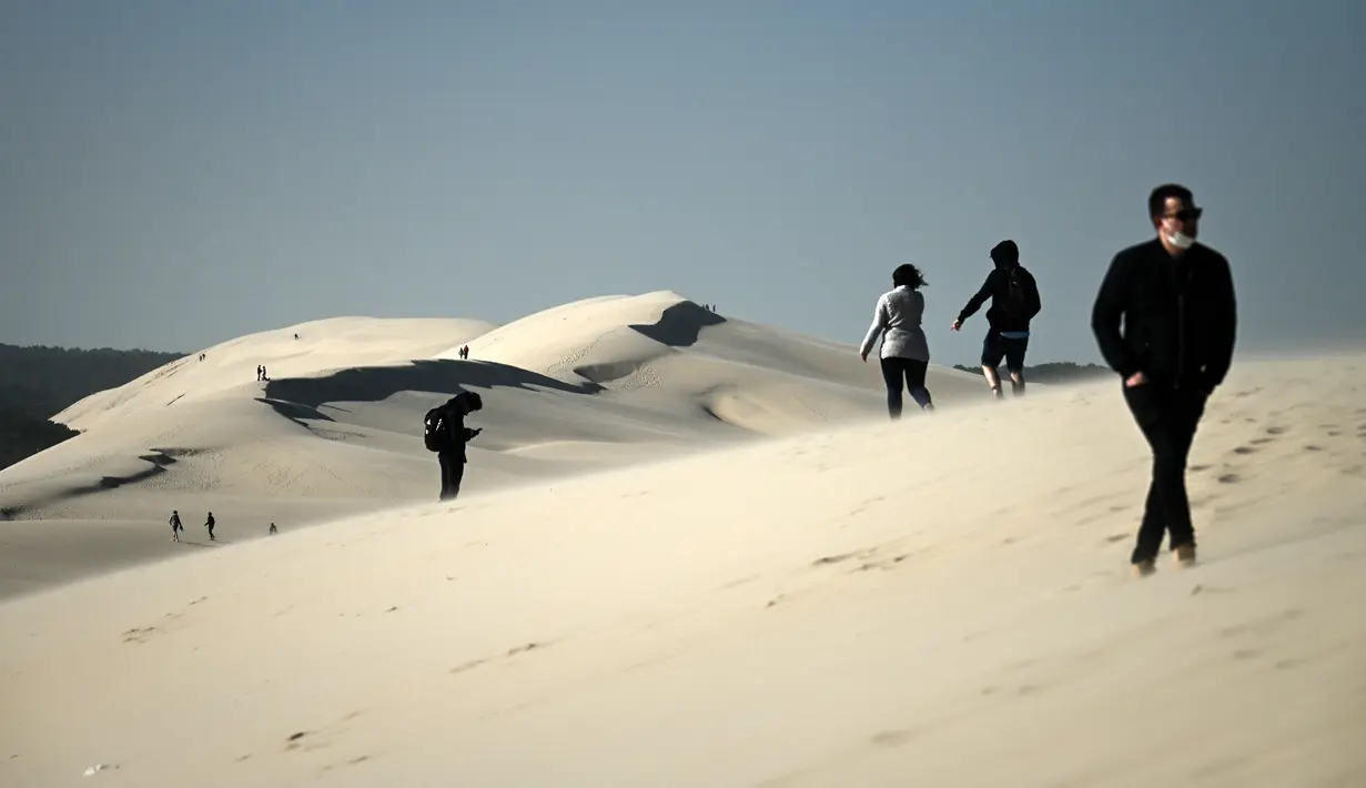 Orang-orang menikmati hari yang cerah di atas gundukan pasir tertinggi di Eropa yang disebut "Dune du Pilat" di La Teste-de-Buch, dekat Teluk Arcachon di Prancis pada 3 April 2021. Memiliki panjang 3 Km dengan lebar 500 meter, The Dune of Pilat memisahkan antara laut dan hutan. (Philippe LOPEZ / AFP