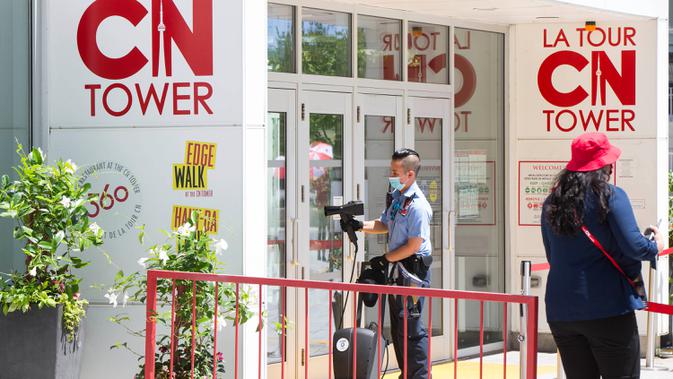 Petugas keamanan membersihkan pegangan pintu di pintu masuk CN Tower di Toronto, Kanada, pada 15 Juli 2020. Setelah ditutup akibat pandemi COVID-19, CN Tower dibuka kembali mulai Rabu (15/7), dengan pengunjung diwajibkan mengenakan masker atau penutup wajah di dalam menara tersebut. (Xinhua/Zou Zhen