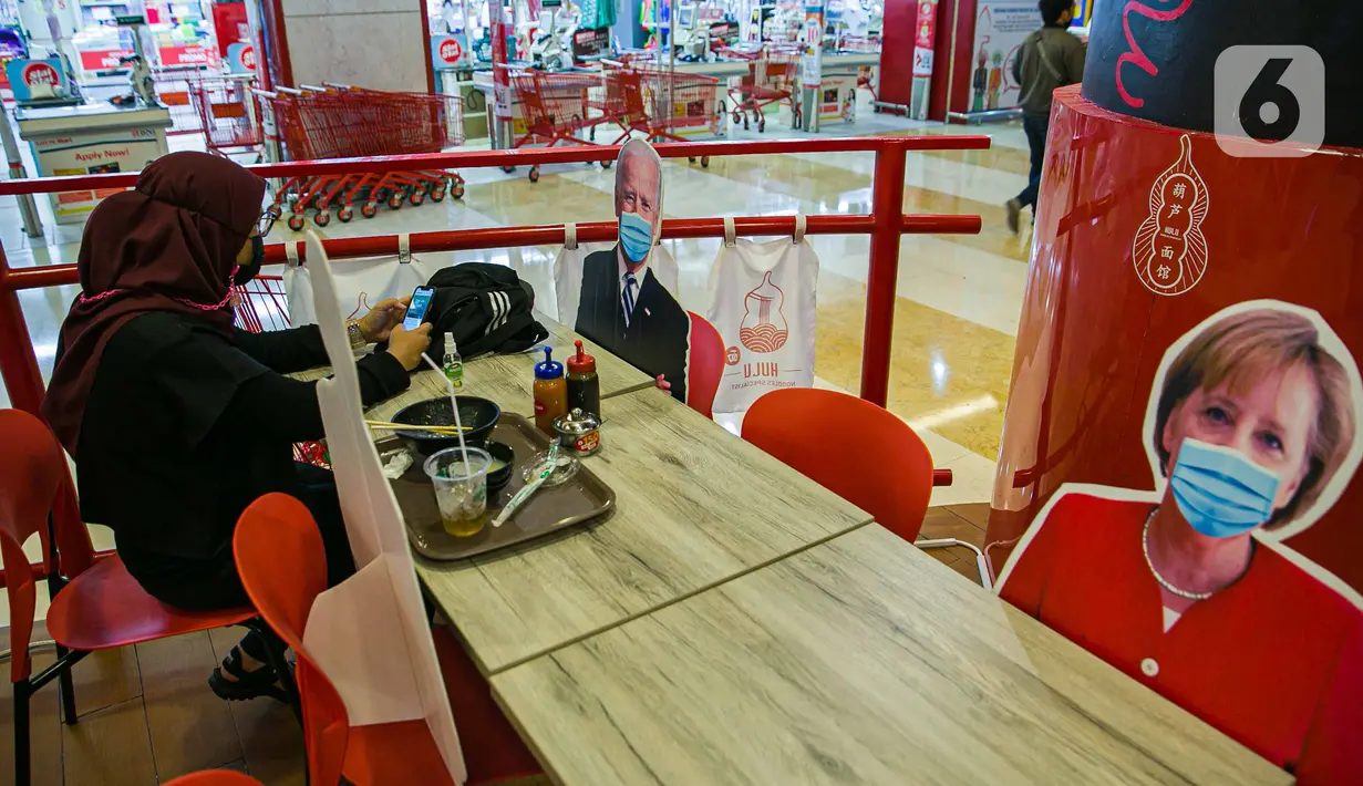 Pengunjung menikmati makanan di meja yang diberi pembatas banner bergambar karakter kepala negara di Restoran Hulu Hulu, Mall Kuningan City, Jakarta, Senin (1/3/2021). Banner bergambar tersebut berguna untuk pembatas bagi pengunjung yang makan di tempat saat pandemi. (Liputan6.com/Faizal Fanani)