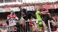 Pelatih Bayer Leverkusen, Xabi Alonso, memanjat tribun penonton saat merayakan gelar juara Bundesliga 2024 bersama suporter di BayArena, Sabtu (18/5/2024). (AP Photo/Martin Meissner)