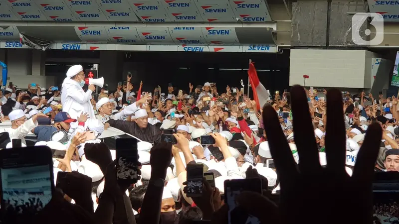 Rizieq Shihab menyapa massa yang menunggunya di Terminal 3 Kedatangan Bandara Soekarno-Hatta, Tangerang, Selasa (10/11/2020). Pimpinan FPI dan rombongan tiba di Tanah Air dengan menumpang pesawat Saudi Arabia Airlines SV816, rute Jeddah-Jakarta. (Liputan6.com/Herman Zakharia)