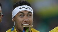 Pemain Timnas Brasil Neymar (10) mengigit medali emas setelah mengalahkan tim kesebelasan Jerman dalam adu penalti di partai final turnamen sepak bola Olimpiade Rio 2016 di Brasil (20/08) (REUTERS / Bruno Kelly)