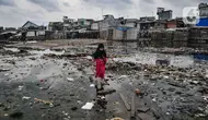 Seorang anak melintasi genangan sampah di permukiman kumuh Muara Baru, Jakarta, Rabu (19/1/2022). Badan Pusat Statistik (BPS) mencatat angka kemiskinan Indonesia turun menjadi 26,5 juta orang per September 2021 dari sebelumnya mencapai 27,54 juta orang pada Maret 2021. (merdeka.com/Iqbal S Nugroho)