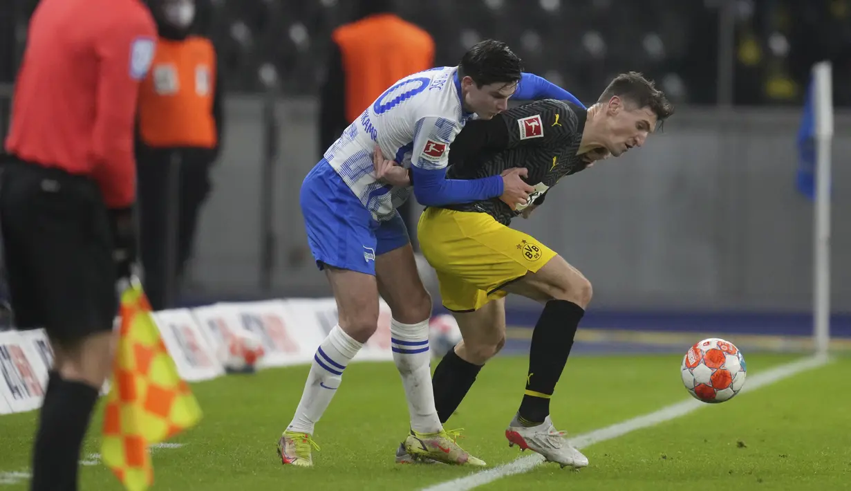 Gelandang Hertha Berlin Jurgen Ekkelenkamp berebut bola dengan bek Borussia Dortmund Thomas Meunier pada laga pekan ke-17 Liga Jerman di Olympiastadion, Minggu (19/12/2021) dinihari WIB. Tuan rumah Hertha Berlin mempermalukan Dortmund dengan skor 3-2. (AP Photo/Michael Sohn)