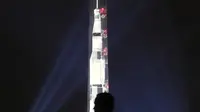 Orang-orang menyaksikan proyeksi roket NASA, Saturn V, di Monumen Washington menandai peringatan 50 tahun misi Apollo 11 ke bulan di National Mall, Washington, Selasa (16/7/2019). Pada 16 Juli 1969, NASA mencatatkan sejarah dengan melakukan peluncuran Apollo 11. (Mark Wilson/Getty Images/AFP)
