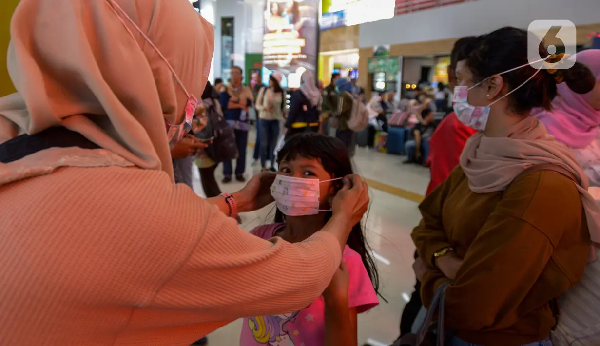 Seorang anak dipakaikan masker saat berada di Stasiun Gambir, Jakarta Pusat, Jumat (31/01). Dalam rangka pencegahan Virus Corona, PT Kereta Api Indonesia (persero) melakukan sosialisasi kepada penumpang kereta api dengan membagi-bagikan masker di stasiun Gambir. (merdeka.com/Imam Buhori)