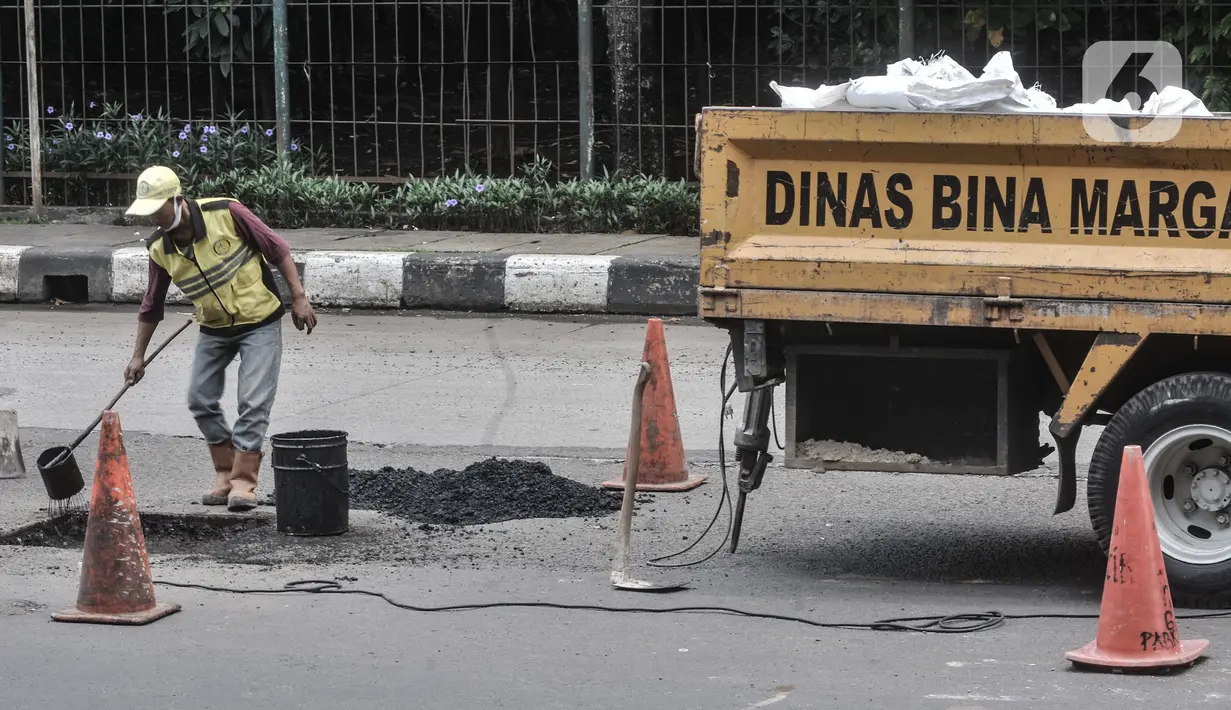 Pekerja meratakan aspal saat perbaikan jalan berlubang di Jalan DI Panjaitan, Cawang, Jakarta, Senin (25/1/2021). Perbaikan jalan rusak dan berlubang akibat sering tergenang banjir di kawasan tersebut dilakukan untuk mengantisipasi terjadinya kecelakaan pengendara. (merdeka.com/Iqbal S Nugroho)