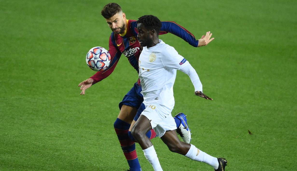 Bek Barcelona, Gerard Pique, berebut bola dengan gelandang Ferencvaros, Tokmac Nguen, pada matchday 1 Grup G Liga Champions 2020/2021 di Camp Nou, Rabu (21/10/2020) dini hari WIB. Barcelona menang 5-1 atas Ferencvaros. (AFP/Lluis Gene)