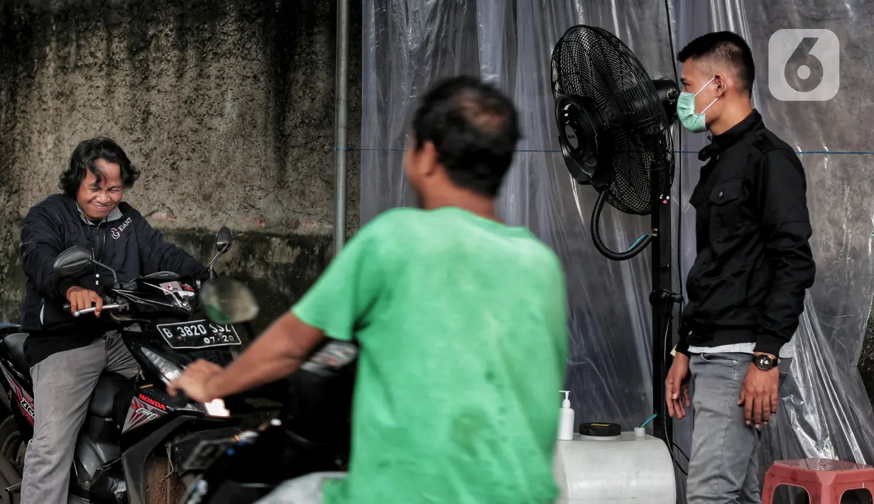 Pengendara sepeda motor disemprot cairan disinfektan saat akan memasuki pemukiman warga di kawasan H. Gari, Pesanggrahan, Jakarta, Jumat (3/4/2020). Penyemprotan secara swadaya tersebut dilakukan warga untuk mencegah penyebaran virus corona COVID-19. (Liputan6.com/Johan Tallo)
